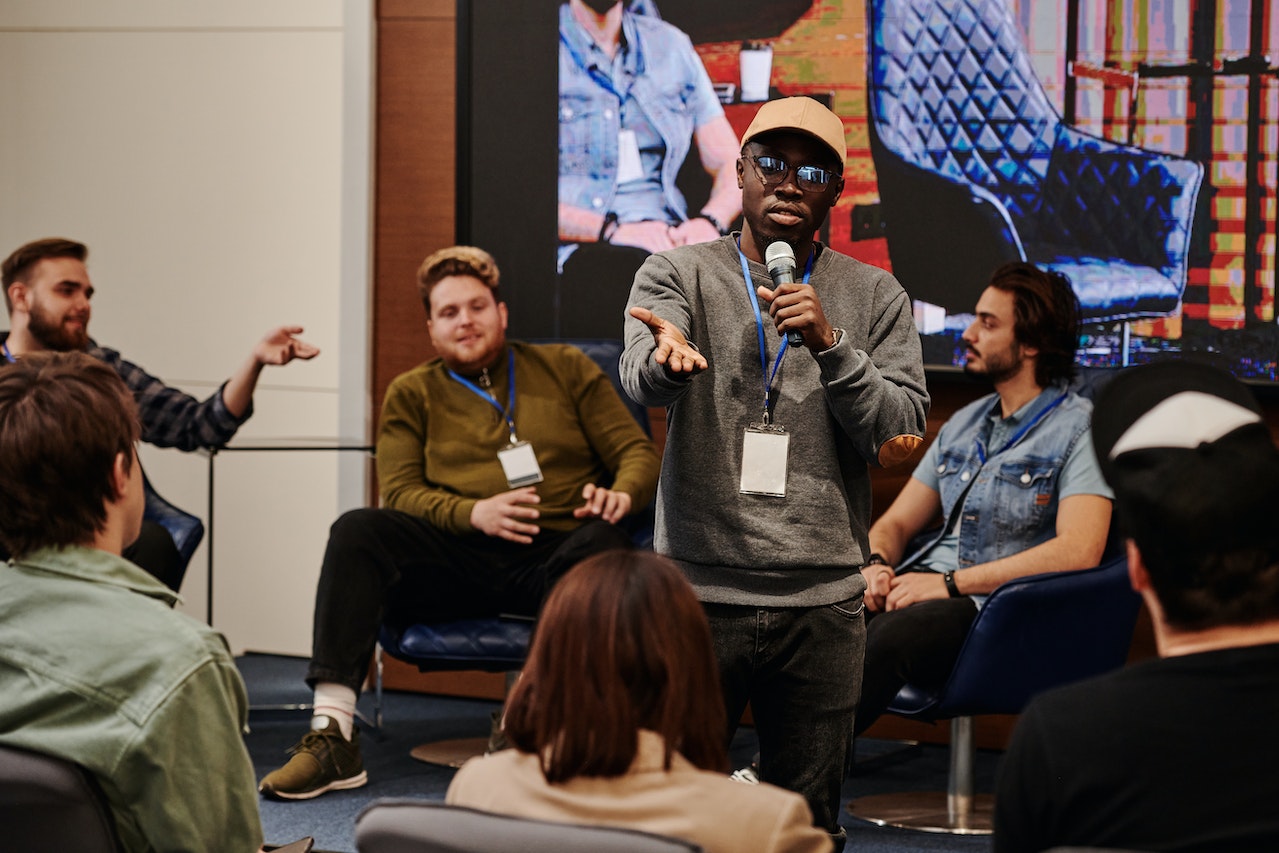 confident-man-with-sunglasses-giving-speaking-in-public-with-microphone-communication-coach